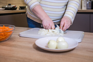 Women's hands chopping onions on a chopping board for pilaf. Cooking in the kitchen. Cook recipe step-by-step. Pilaf recipe in pictures.