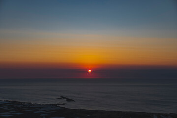 Obraz premium The sun at orange sunset just above the surface of the sea