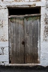 Destroyed white wall of abandoned building with wooden door