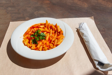 Penne arrabiata - traditional italian pasta with spicy sauce on a table