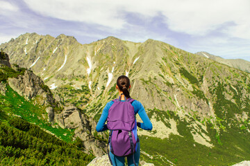 Back view of woman traveler with backpack standing and looking to the beautiful nature of the...