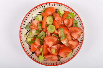 A top-down shot shows a colorful bowl filled with a fresh tomato salad mixed with green onions and basil