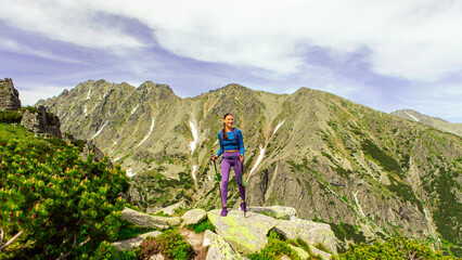 Fototapeta premium Full length shot of woman traveler enjoying mountain scenery, standing on top of the mountains at sunny summer day, free space