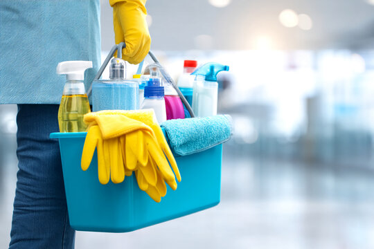Blue cleaning bucket with cleaning supplies, yellow gloves and a towel, held by a person, showcasing cleanliness and hygiene services