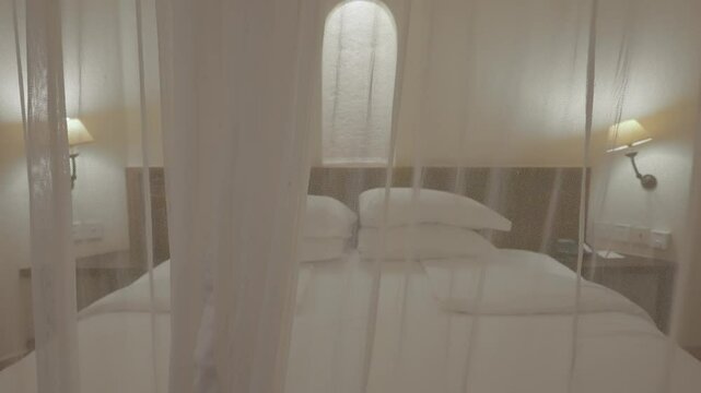 Camera moving towards hotel bed in suite with mosquito net or canopy over it. Luxury resort in African country. Five 5 star hotel room with protection against bugs and insect bites at night