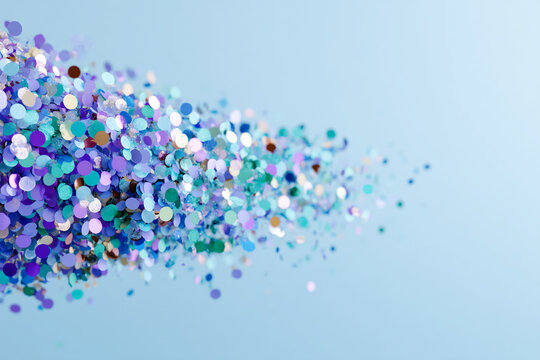 Pile of iridescent glitter confetti on light-blue background, creating a festive and joyful mood, ideal for celebration or party designs, free space for text