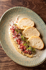 A beautifully plated dish of beef tartare with cream sauce, garnished with microgreens and served alongside toasted bread slices, highlighting gourmet culinary presentation.