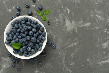 Bowl with fresh bright blueberries on concrete background,top view