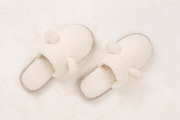 Soft teddy slippers on concrete background, top view