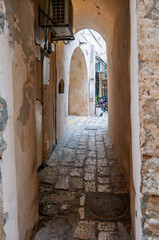 Fototapeta na wymiar A narrow alleyway with a brick floor and a metal vent above it