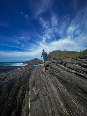 A young man walks on the rocks along the shore of a beach in the town of Búzios, the main tourist destination in the lakes region of Rio de Janeiro.