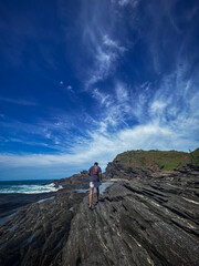 A young man walks on the rocks along the shore of a beach in the town of Búzios, the main tourist destination in the lakes region of Rio de Janeiro.