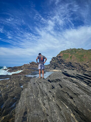 A young man walks on the rocks along the shore of a beach in the town of Búzios, the main tourist destination in the lakes region of Rio de Janeiro.