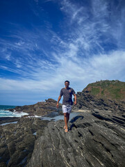 A young man walks on the rocks along the shore of a beach in the town of Búzios, the main tourist destination in the lakes region of Rio de Janeiro.