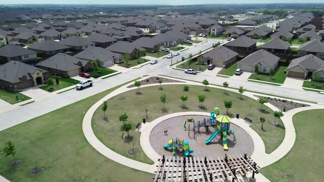Modern circular children playground with climbing structures, slides, spring riders, wooden pergola in Princeton, growing small town in Dallas Metroplex, Collin County in North Texas, flyover