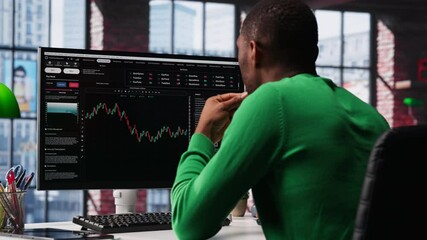 Day trader uses computer to purchase stocks that might perform well and selling ones that might drop in value. Forex trader browsing though stock exchange portfolio pages at PC desk. Camera A.