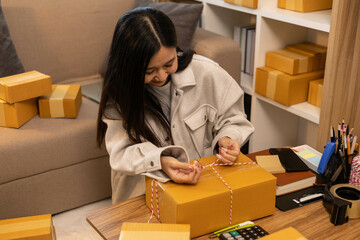 A woman is holding two boxes and smiling. She is sitting in front of a laptop. The boxes are brown and appear to be gifts. The woman seems happy and excited about the boxes
