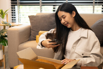 A woman is holding two boxes and smiling. She is sitting in front of a laptop. The boxes are brown and appear to be gifts. The woman seems happy and excited about the boxes
