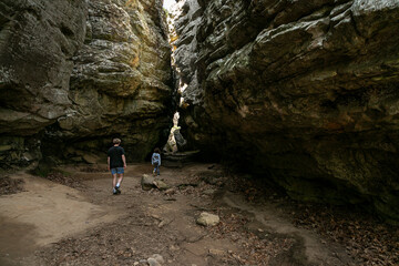 Rear view of Two children walking through a scenic cave in the Ozark Mountains on a beautiful nature hike in Petit Jean State Park. Beautiful rock canyon cavern scene
