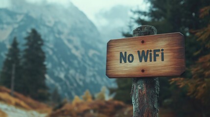 Obraz premium rustic wooden sign, No WiFi, affixed to a weathered post, against a backdrop of majestic, misty mountains.