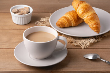 Freshly baked croissants served with a hot cup of coffee on a wooden table in a cozy setting