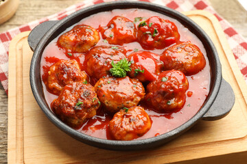 Delicious meatballs with tomato sauce in baking dish on table, closeup