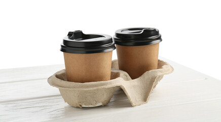 Paper coffee cups in cardboard holder on white wooden table, closeup