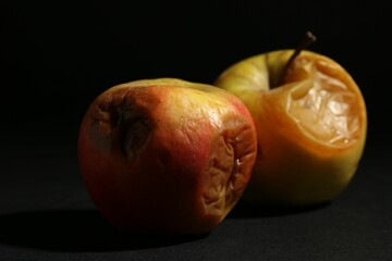 Two rotten apples on black background, closeup