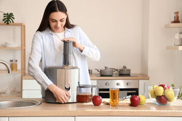 Young woman making apple juice in kitchen