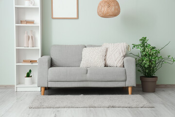 Shelving unit with sofa, houseplant and photo frame near grey wall in living room