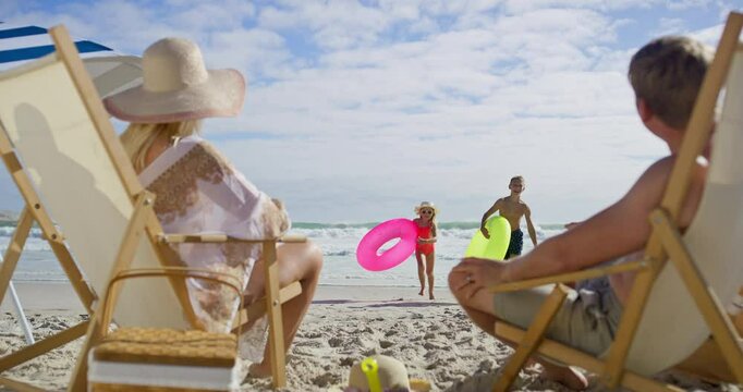 Sea, hug and family fun with kids, beach chair and embrace and running outdoor in sun. Happy, vacation and travel with love, support and care together and playing by ocean on summer holiday in Miami