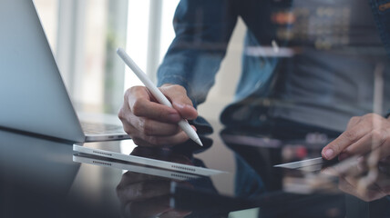 Close up, casual business woman using stylus pen working on digital tablet with laptop computer on table at home office. Graphic designer creates art work via mobile app, freelance at work