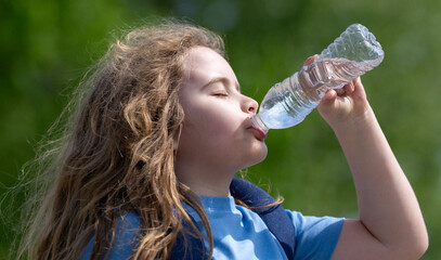 Child drinking water from bottle. Kid refreshing with drink. Thirsty child drink water from plastic...