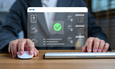 Businessman using computer mouse and keyboard to complete digital document verification process, with holographic checkmark and contract icons, representing online approval and certification.