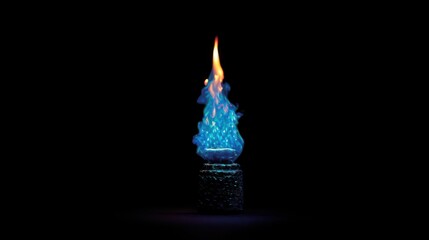 A glowing yellow flame dances atop a burning wax candle in the dark against a cool blue background, radiating a soft candlelight