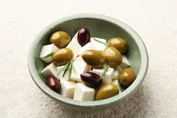 Tasty olives with feta in bowl on table, closeup