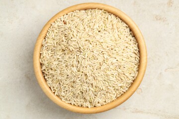 Brown rice in bowl on light grey table, top view