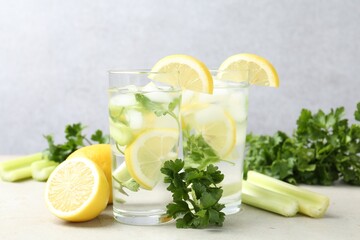 Healthy drink with parsley, lemons and celery on light grey table