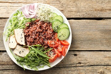 Delicious salad with brown rice on wooden table, top view. Space for text
