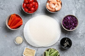 Rice paper sheets and different ingredients on light grey table, flat lay
