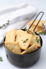 Tasty salty crackers and thyme on white table, closeup