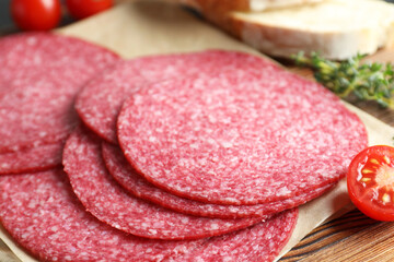 Slices of tasty smoked sausage, tomato, thyme and bread on table, closeup