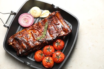 Delicious roasted pork ribs with rosemary, tomatoes and onions on light table, top view