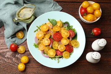 Fresh salad with yellow tomatoes served on wooden table, flat lay