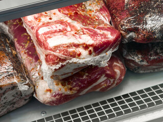 Savory cuts of marinated meats displayed in a butcher shop during a bustling weekend market