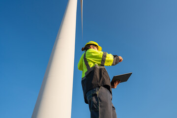 Engineer wearing uniform inspection and survey work in wind turbine farms rotation to generate electricity energy. Maintenance engineer working in wind turbine farm at sunset.
