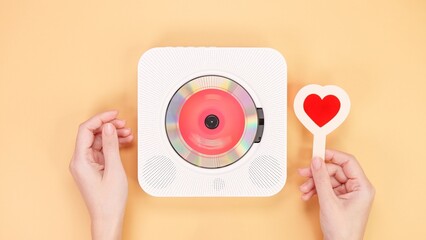 White retro styled portable compact disc player with a red heart on a peach background.