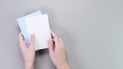 Slender Female Hands Holding Blank Note Cards On A Solid Gray Background