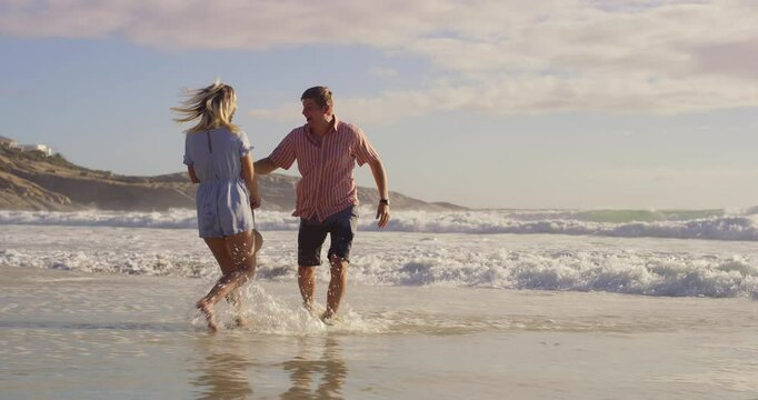 Beach, love and playing in ocean with couple outdoor together for anniversary, honeymoon or romance. Having fun, laughing or smile with man and woman in sea of tropical island paradise for bonding