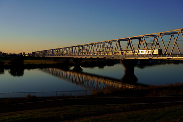 夕陽に染まる鉄橋と輝く車両
